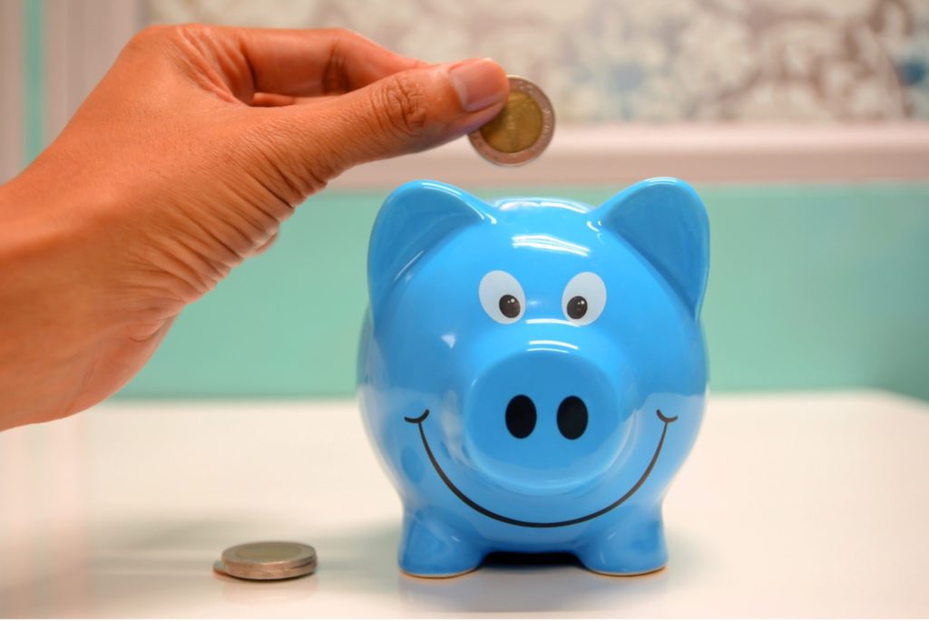 Man inserting a coin in the piggy bank.