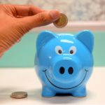 Man inserting a coin in the piggy bank.