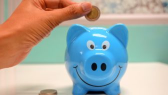 Man inserting a coin in the piggy bank.