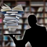A man balancing a heap of books in one hand.