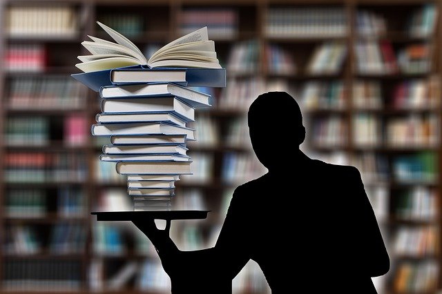 A man balancing a heap of books in one hand.
