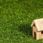 A wooden toy house placed on the grass.