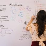“A young woman business leader draws out her vision on a whiteboard.”
