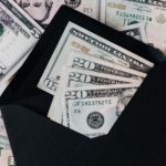 Different denomination money placed in an envelope and around.