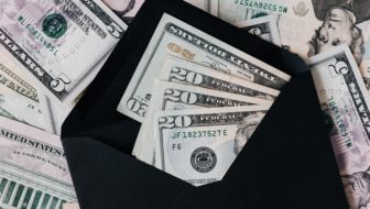 Different denomination money placed in an envelope and around.