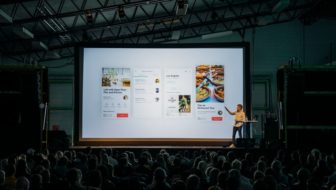 A man presenting on the screen in an event.