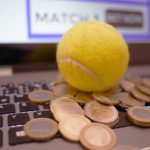 Online Cricket Betting where a ball is placed on the keyboard surrounded by coins.