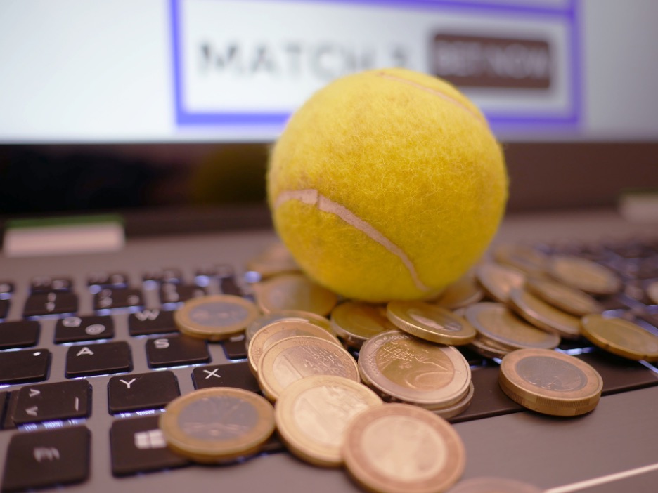 Online Cricket Betting where a ball is placed on the keyboard surrounded by coins.