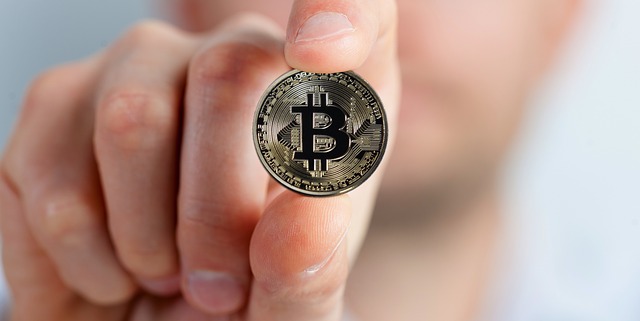 A man holding a Bitcoin between his fingers.