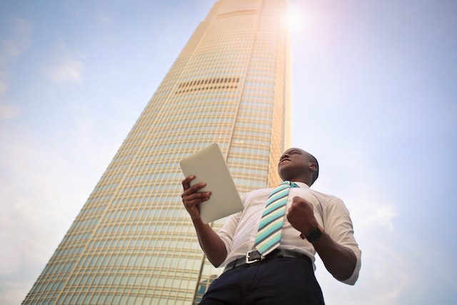 An Entrepreneur holding papers in his hand near a sky scraper.