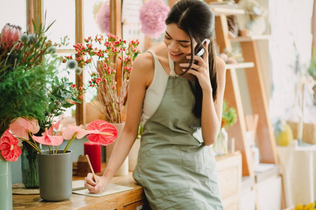 A woman taking orders in a flower shop.