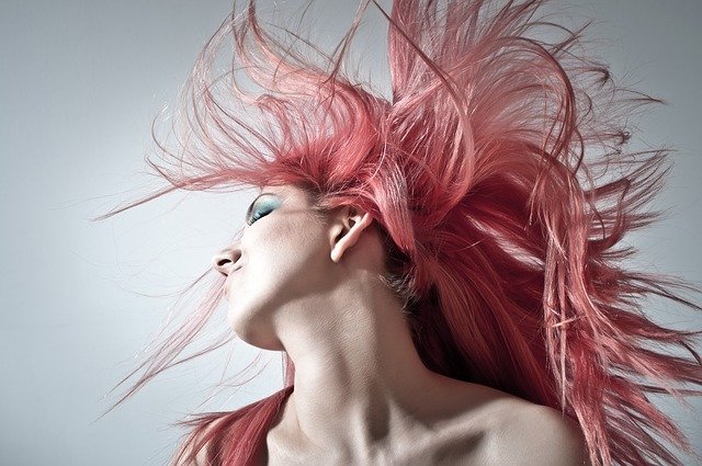 A woman in pink hair posing for a picture.