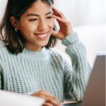 A woman smiling and looking at the screen.