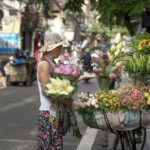 A woman buying flowers from a cycle vendor.