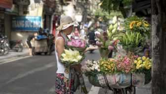 A woman buying flowers from a cycle vendor.