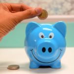 A man inserting coin in a piggy bank.