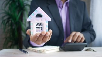 A man holding a toy house.